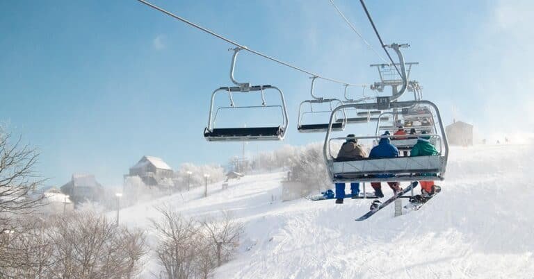 People riding the ski lift up to the top of the mountain.