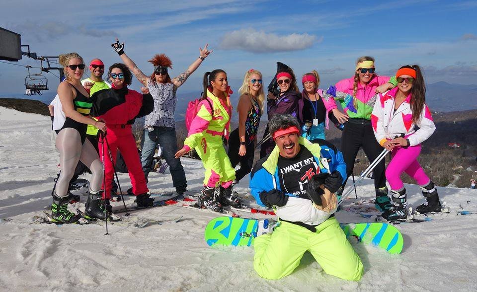 Picture of group of people dressed in 80s retro clothes on top of slopes