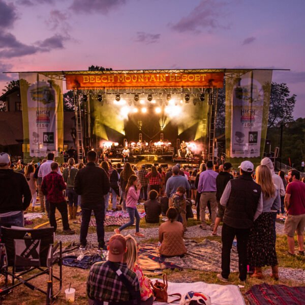 Beech Mountain Resort's summer concert series, featuring musicians performing live music against a scenic backdrop of sunny skies and lush green mountains.